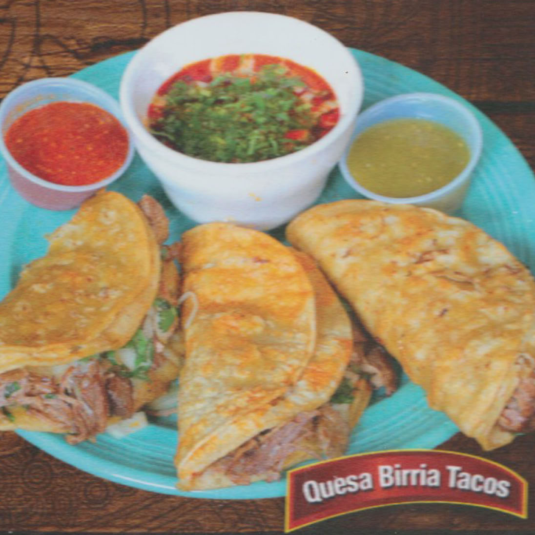 Close-up of assorted Mexican tacos with fresh vegetables, herbs, and vibrant garnishes on a wooden table.